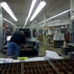 Bob, a press operator, pulls a signature from the Heidelberg press to test and calibrate its color levels.
